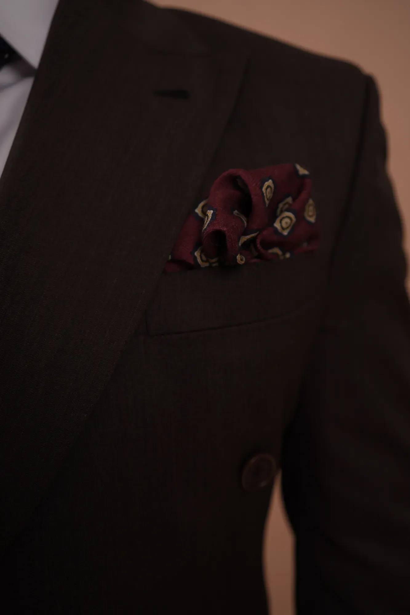 A burgundy silk pocket square in the breast pocket of a dark jacket