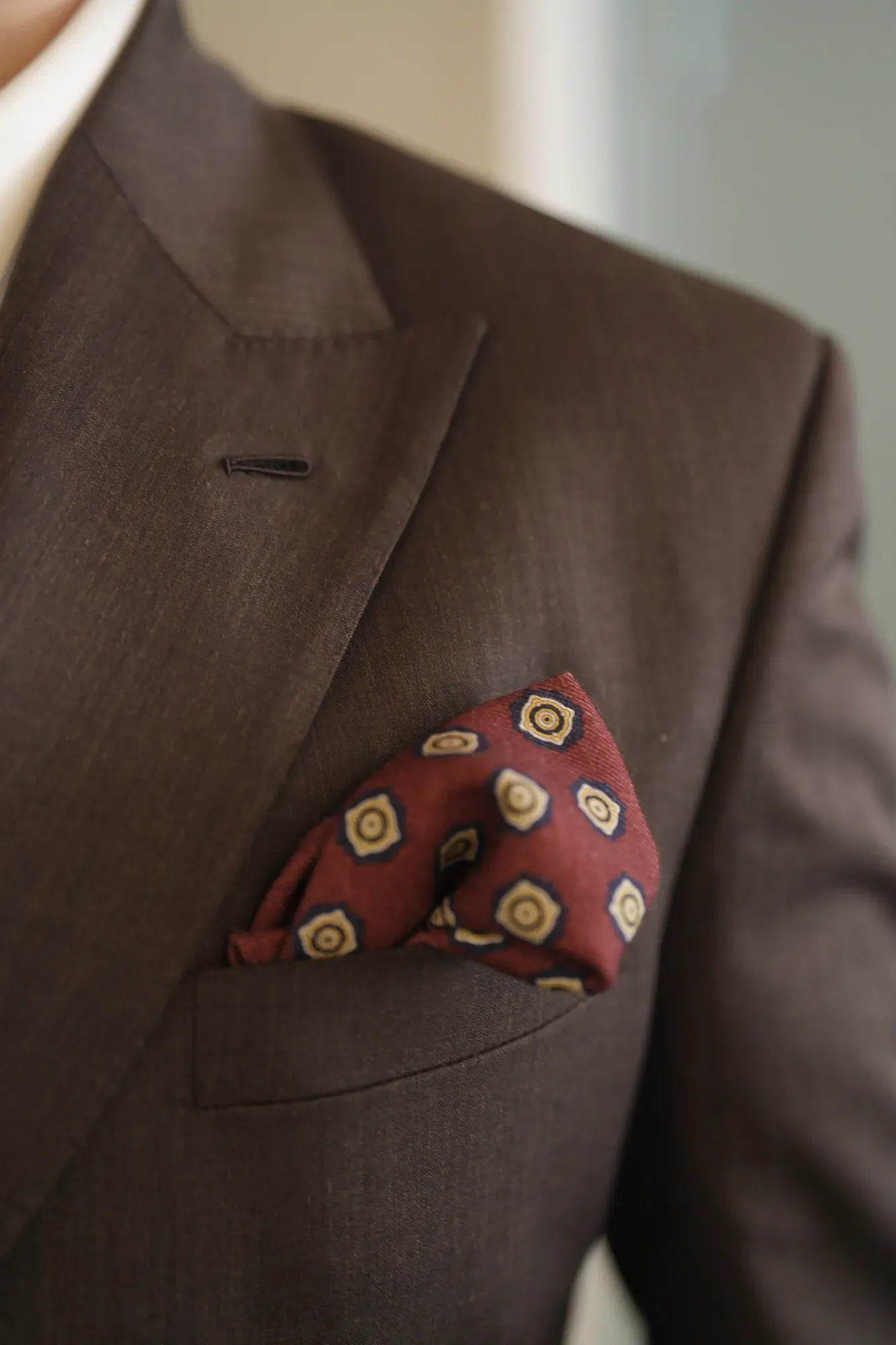 A patterned silk pocket square in a brown jacket